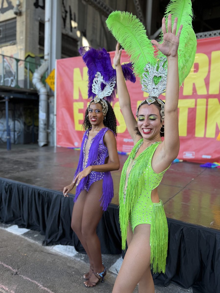 Two dancers in purple and green feathers on the Cultural Stage