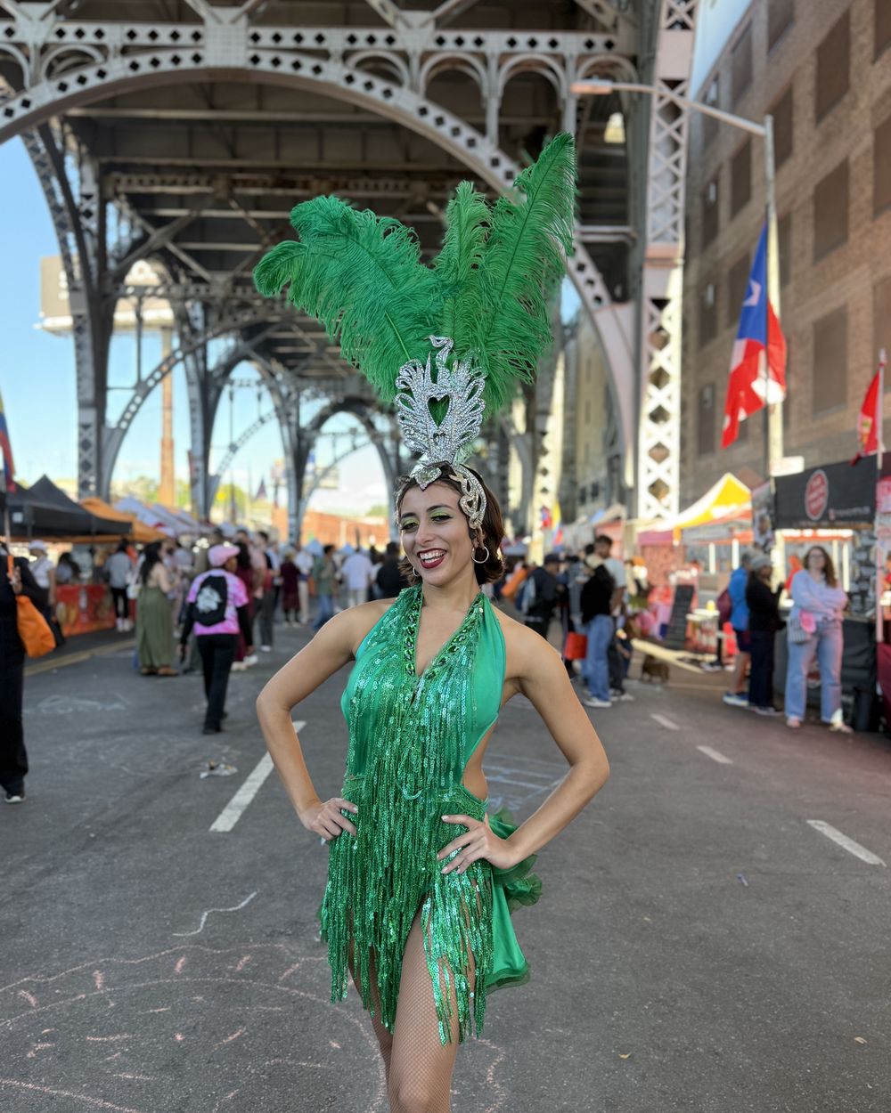 A dancer in green feathers on the block under the viaduct