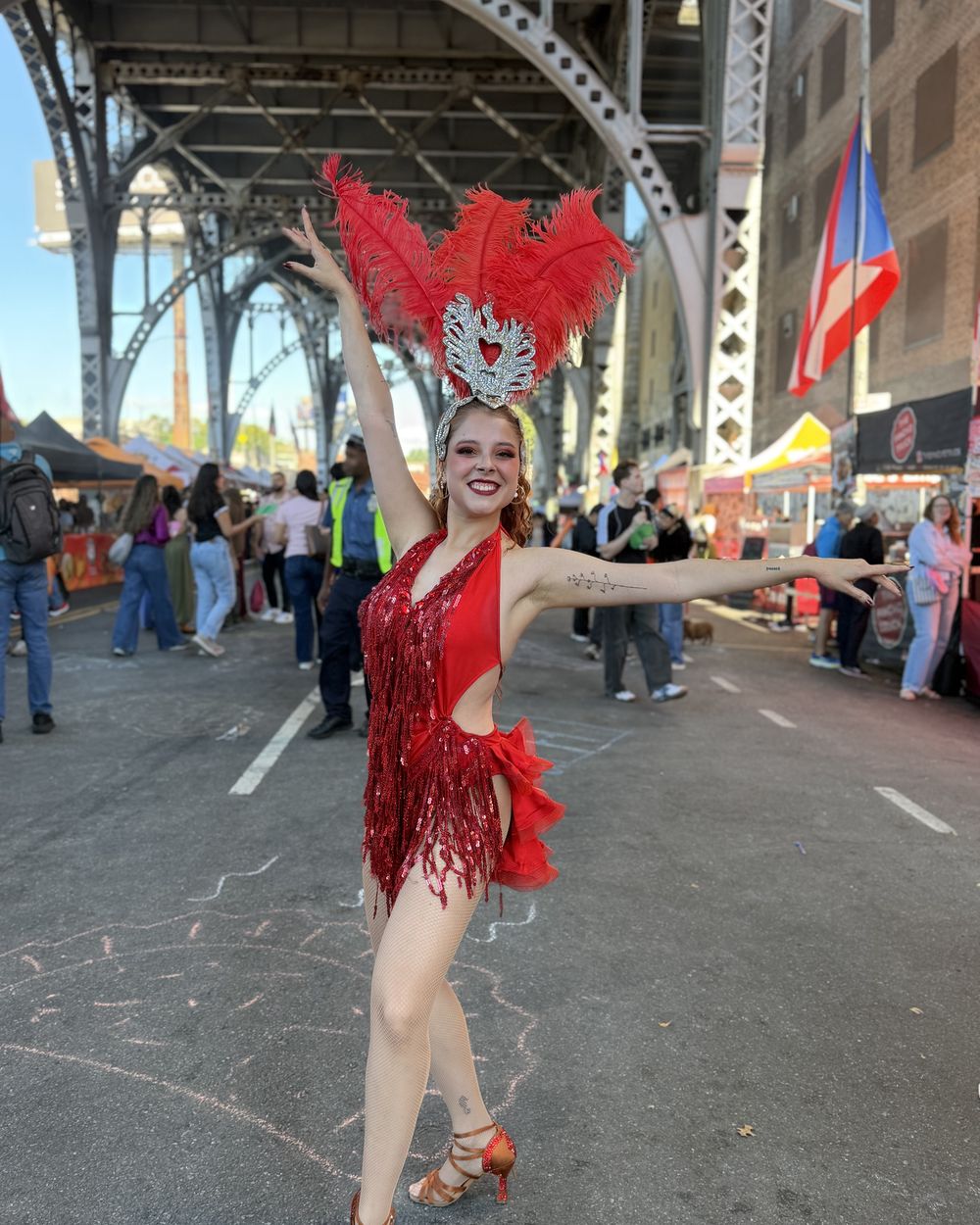 A dancer in red feathers under the viaduct at Latin Food Fest NYC