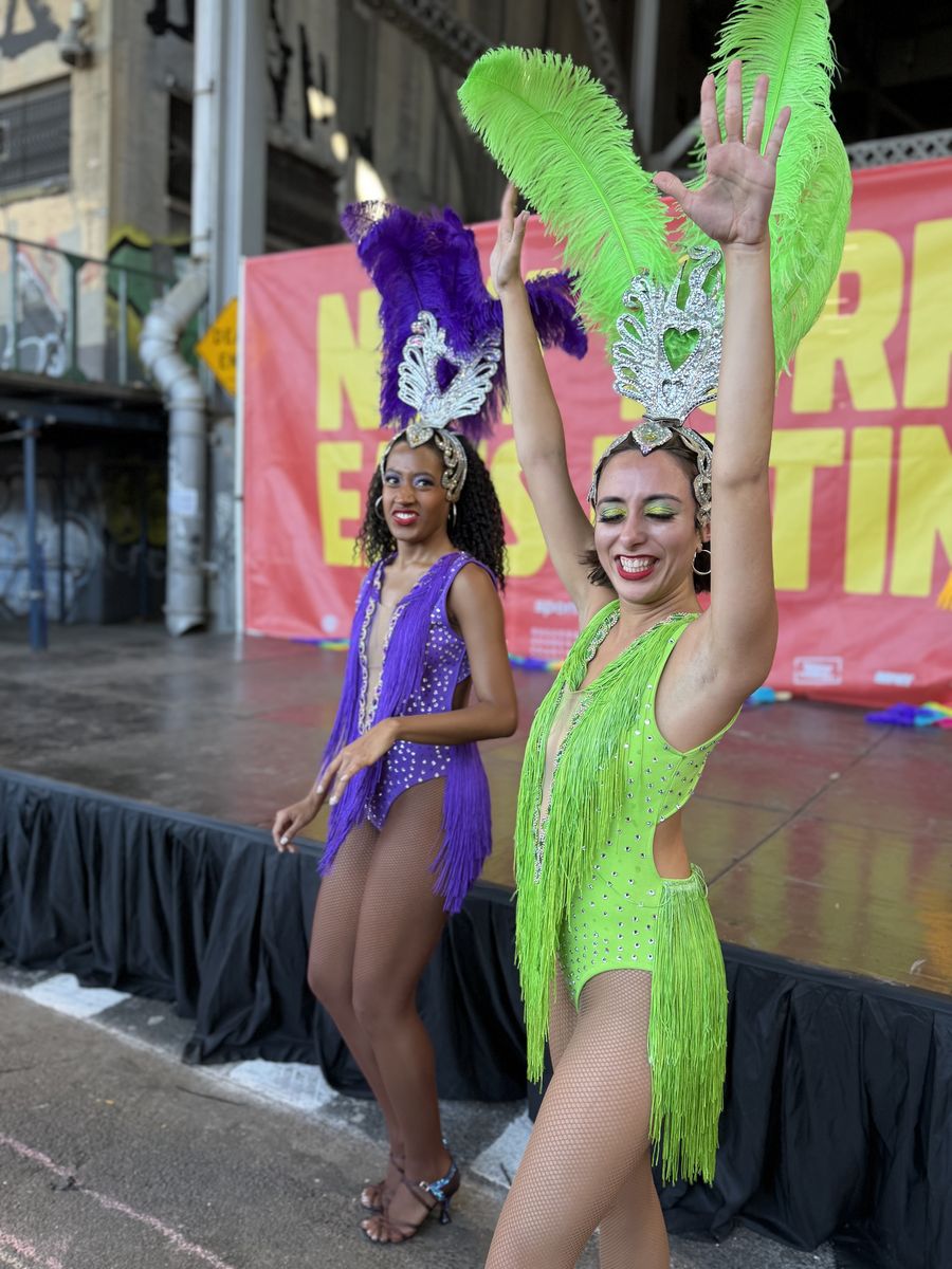 Two samba dancers in purple and green feathers on the Cultural Stage